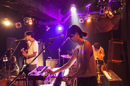 A group of musicians are playing music on a stage during a live event at a night bar.